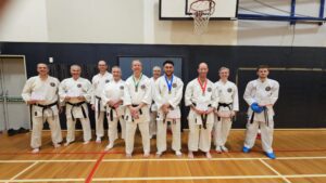10 black belt wearing karate students holding up there certificates of participation
