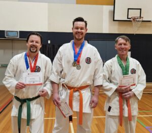 three karate students showing off their medals